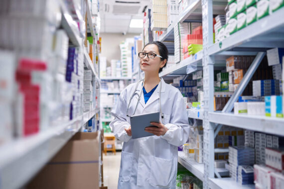 Asia Female Pharmacist Using Digital Tablet while Taking Inventory